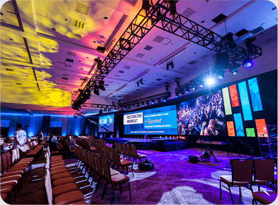 An event space with colorful lighting and large screens
